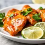 Sweet Chili Lime Chicken served on a white plate with lime wedges and cilantro garnish